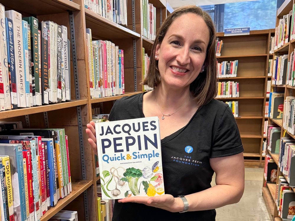 Marissa Ain holding a copy of Jacques Pepin's Quick and Simple cookbook