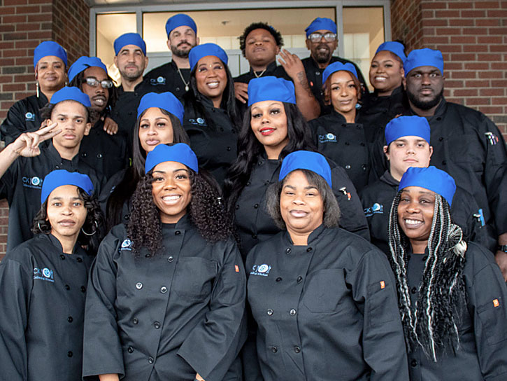Culinary students in graduation attire at Cathedral Kitchen