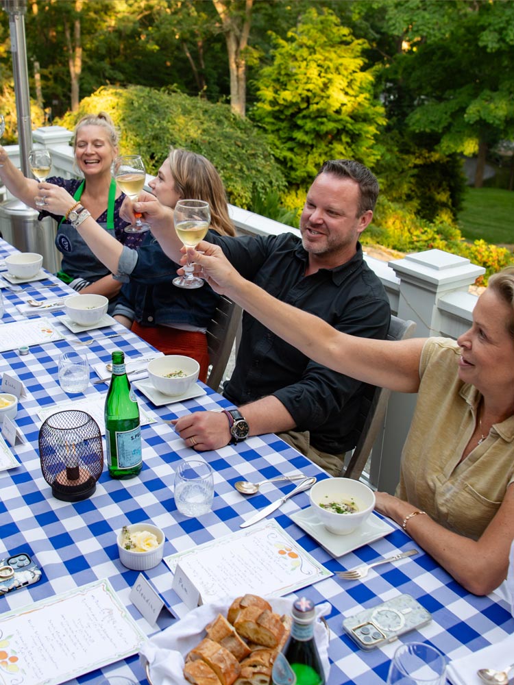 Image of a dinner table with guests raising their glasses in a toast