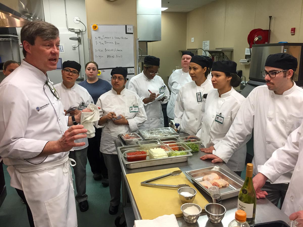 Rollie Wesen in the kitchen instructing culinary students