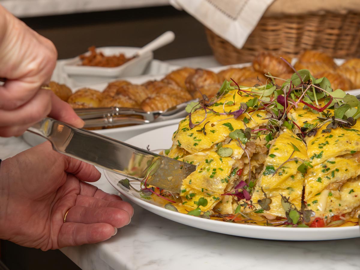 Person cutting a portion of an egg omelette